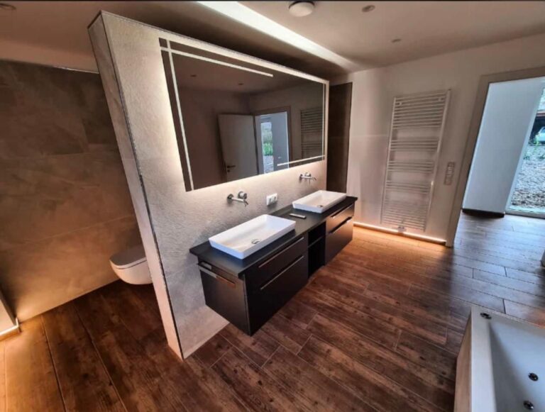 Badezimmer mit Bodenfliesen in Holzoptik, Doppelwaschtisch und indirekter LED-Beleuchtung