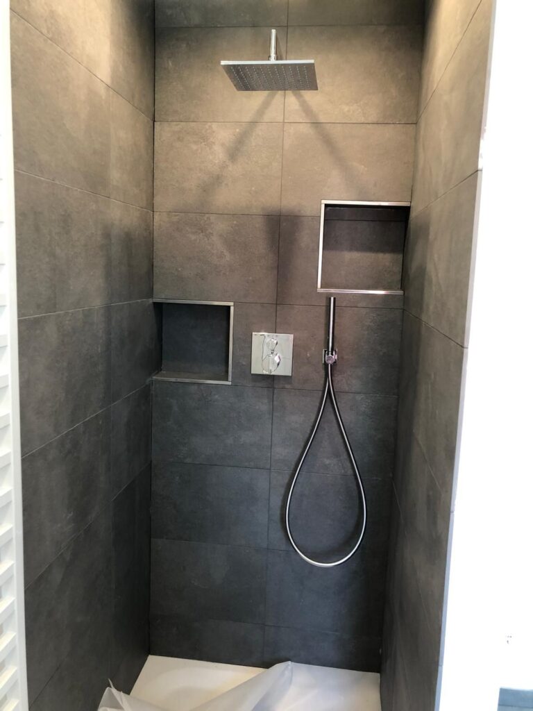 Begehbare Dusche mit dunklen Großformatfliesen, Regenbrause und Wandnische