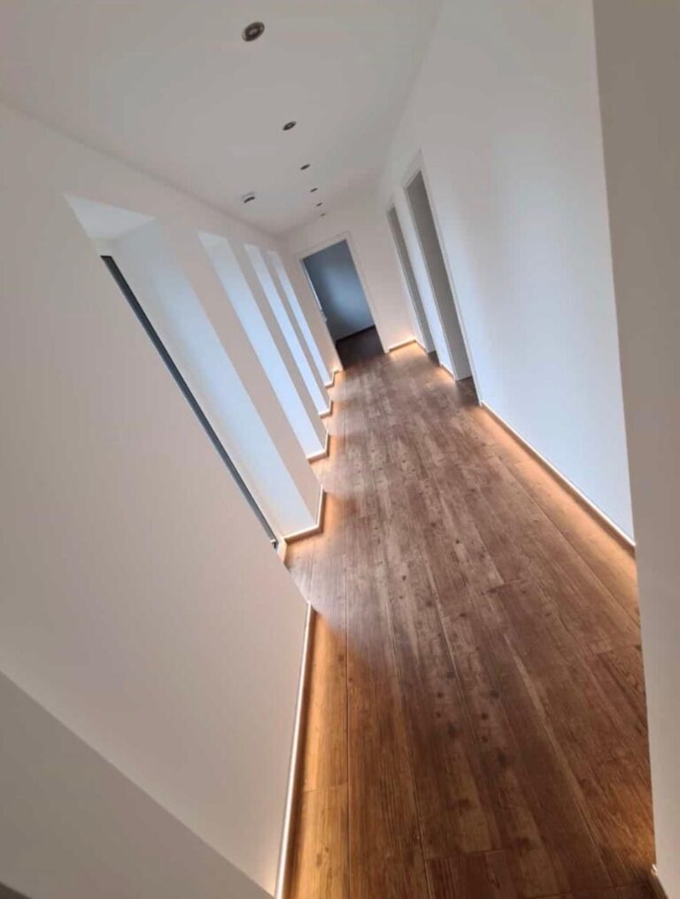 Flur mit Bodenfliesen in Holzoptik und indirekter LED-Sockelbeleuchtung