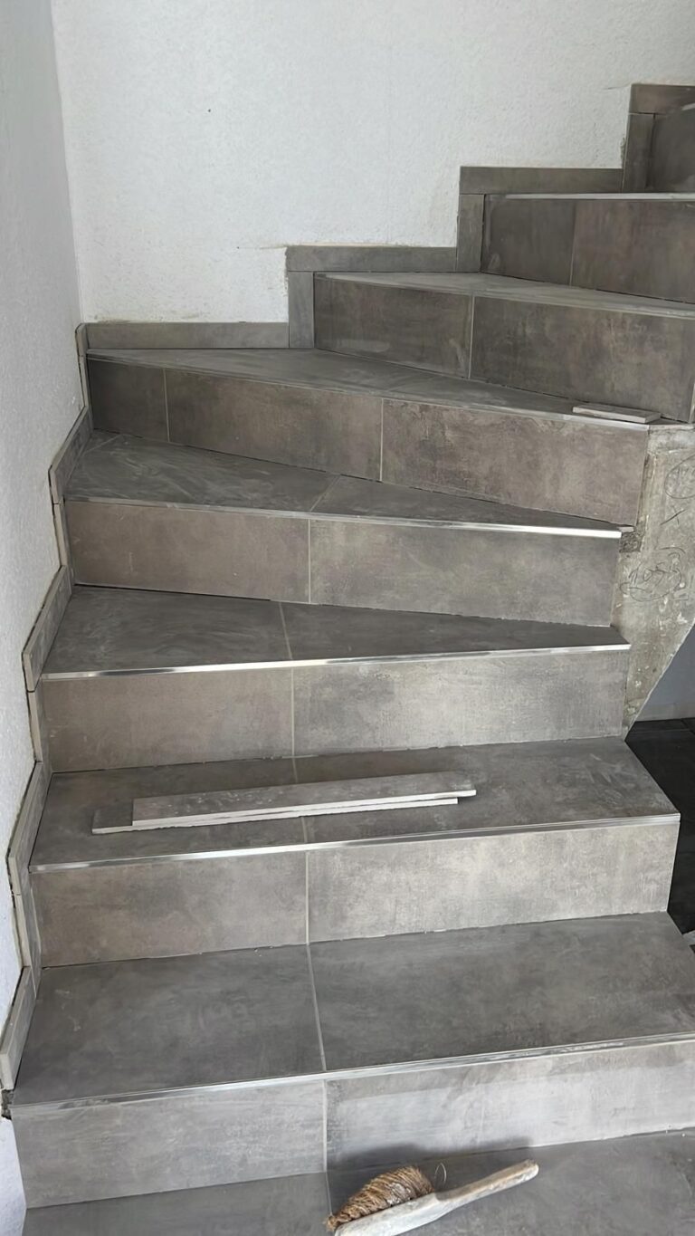 Treppe mit grauen Feinsteinzeug-Fliesen und Treppenkantenprofilen